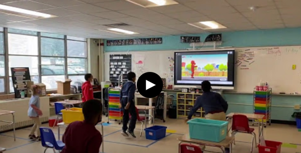 Syracuse Academy of Science and Citizenship elementary school students participate in a quick stretch break by jumping, and dancing to a Go Noodle exercise video.
