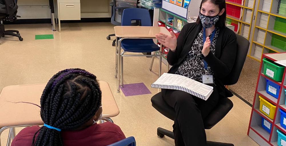 Syracuse Academy of Science and Citizenship elementary school teacher Mrs. Daniel helps a student with their reading and comprehension skills.